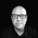 Black and white portrait of a man with glasses and a serious expression.