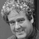 Portrait of Michael A. with curly hair, smiling, in black and white.