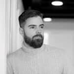 Black and white portrait of a bearded man with short hair in a sweater.