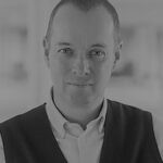 Portrait of Nick B. in professional attire, indoor setting.