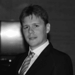 Portrait of Nicolas M. in formal attire, professional headshot.