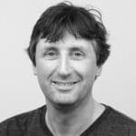Black and white portrait of a smiling man with dark hair.