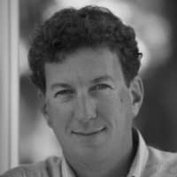 Black and white portrait of Peter H. with curly hair and a slight smile.