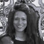 Smiling woman with long hair in front of decorative background.