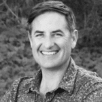 Portrait of Reed F. smiling outdoors, professional headshot.
