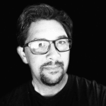 Black and white portrait of a man with glasses and facial hair.