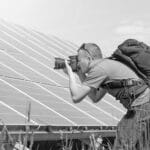 Photographer taking photos of solar panels in a field.