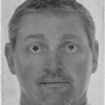 Black and white portrait of a man with short hair and neutral expression.
