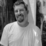Portrait of Scott S. smiling outdoors in black and white.