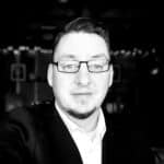 Portrait of Scott W. in a professional setting, wearing glasses and a suit.
