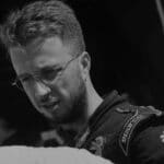 Portrait of a young male race car driver with glasses and a racing suit.
