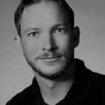 Black and white portrait of a young man with short hair and a slight smile.