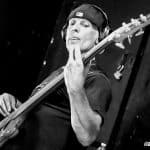 Man playing bass guitar with headphones, black and white image.