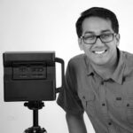 Man smiling with 3D laser scanner in black and white.
