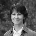 Portrait of Liz M. smiling outdoors in black and white.