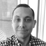 Black and white portrait of a man with short hair and a checkered shirt.