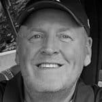 Portrait of John M. smiling, wearing a cap, outdoors in Lockport NY.