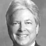 Black and white portrait of John R. with smiling face and professional attire.
