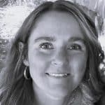 Portrait of a smiling woman with wavy hair and hoop earrings.