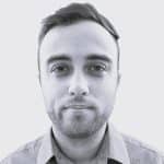 Portrait of a young man with short hair and beard in grayscale.
