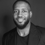 Black and white portrait of Nate R. smiling, wearing a blazer.