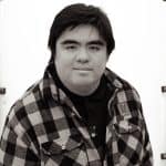 Young man with dark hair wearing a plaid shirt, facing camera.
