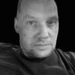 Black and white portrait of a man with short hair and beard.