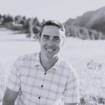 Portrait of Chris T. smiling outdoors with mountains in background.