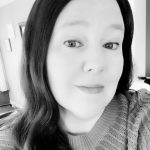 Portrait of Janice G. with dark hair and light sweater in black and white.