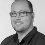 Portrait of Mark L. from Texas, wearing glasses and a black shirt.