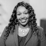 Smiling woman with curly hair in professional attire.