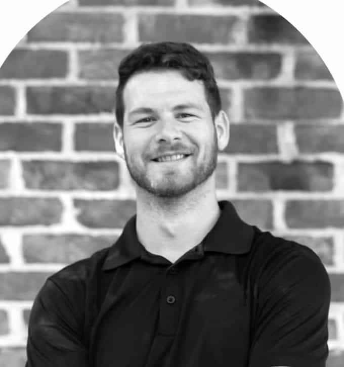 Portrait of Zackary G. smiling in front of a brick wall.