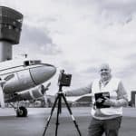 Man using drone equipment near airplane at airport.