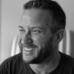 Portrait of Brent W. smiling, looking to the side, in a professional setting.