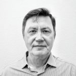 Black and white portrait of Dmitry L. in front of a plain wall.
