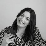 Woman smiling while looking at her phone in black and white.