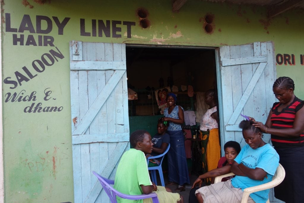 Linet braids a customer's hair. 