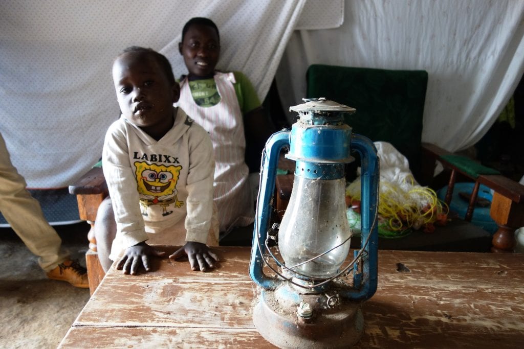 Charles' children next to the polluting kerosene lamp. 