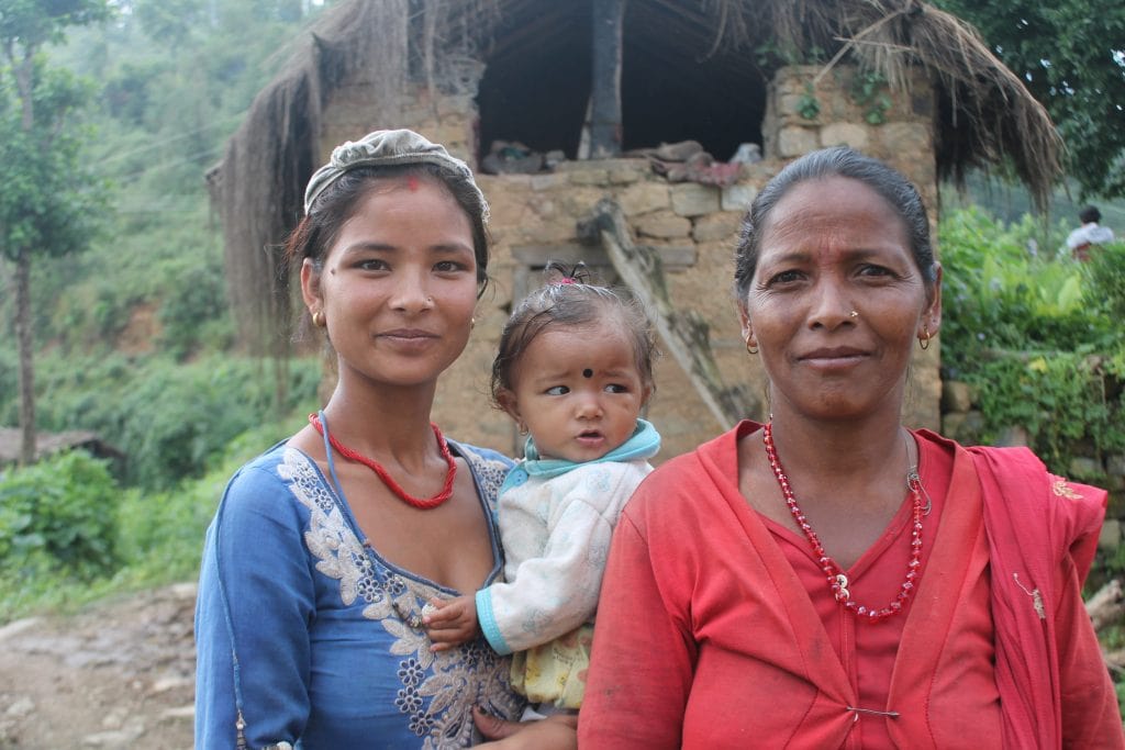 Prabitra holding her young daughter standing with her mother in law 