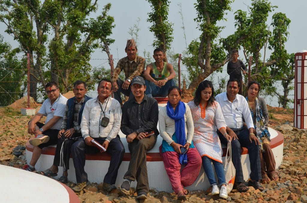 A group of community members smiling and sitting on one of the round water tanks. 