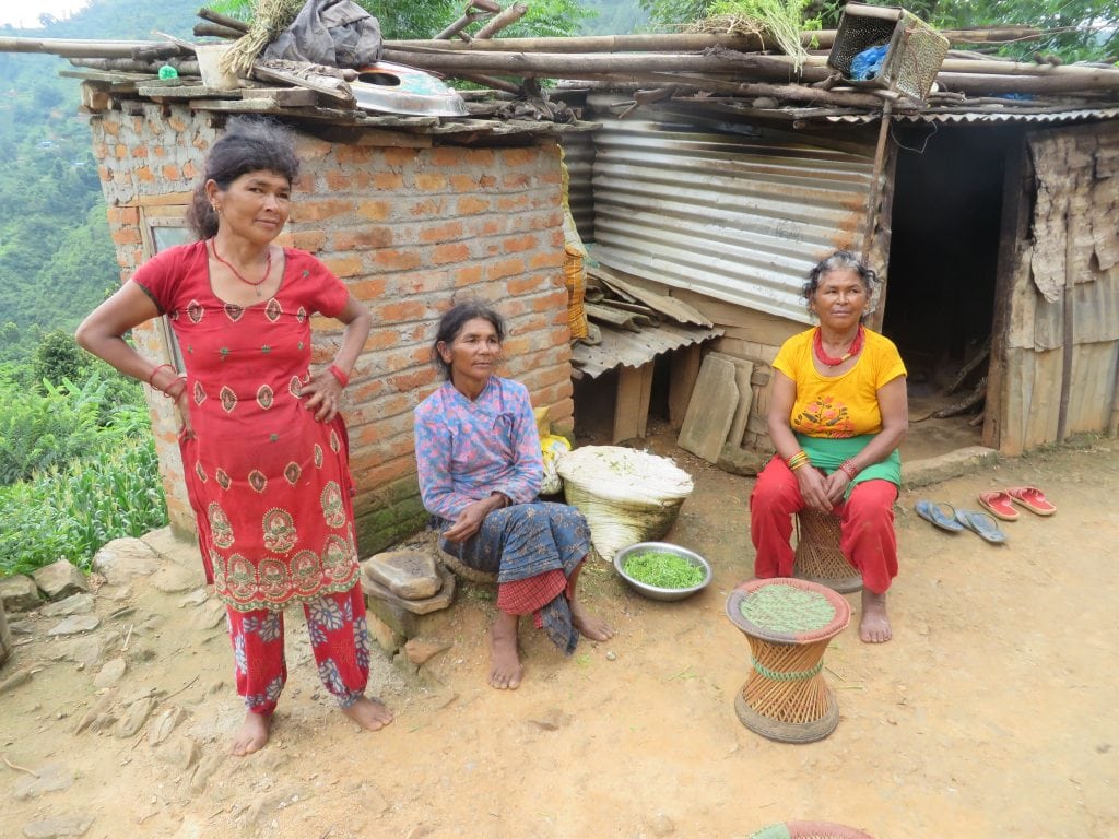 Three women sit outside a building.