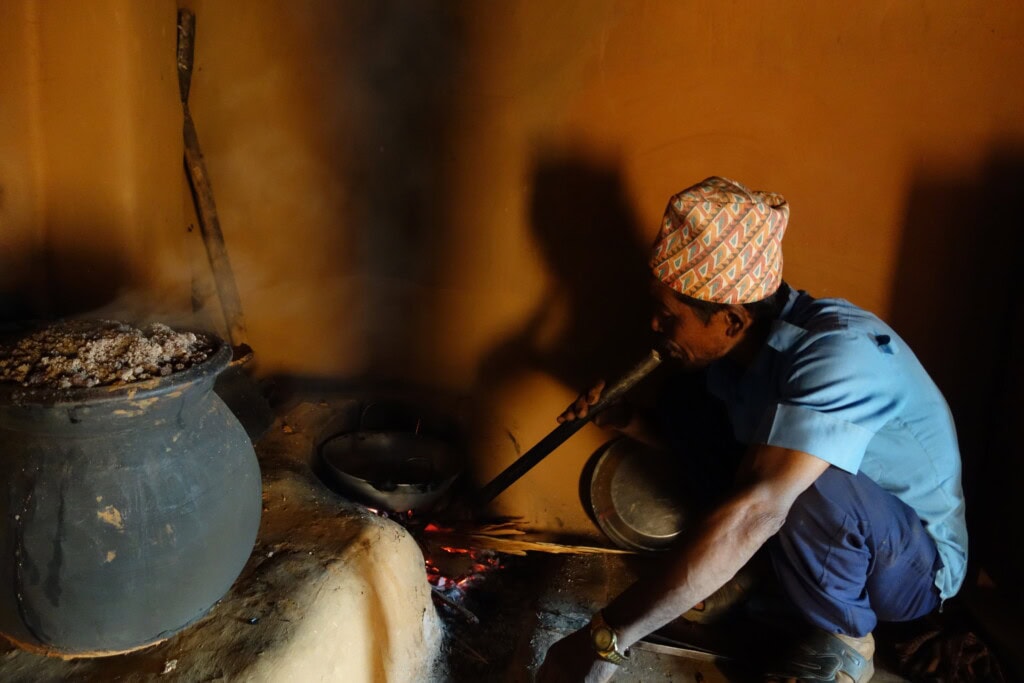 A man sitting in front of a traditional cooking stove in Nepal