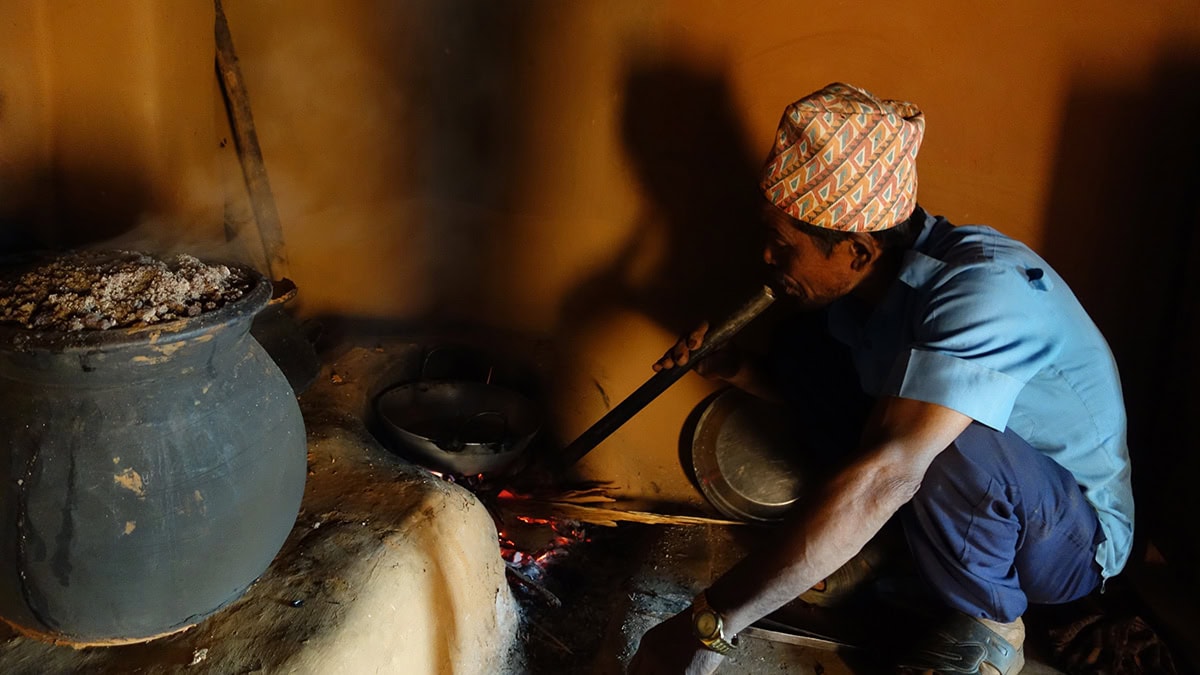 A man sitting in front of a traditional cooking stove in Nepal