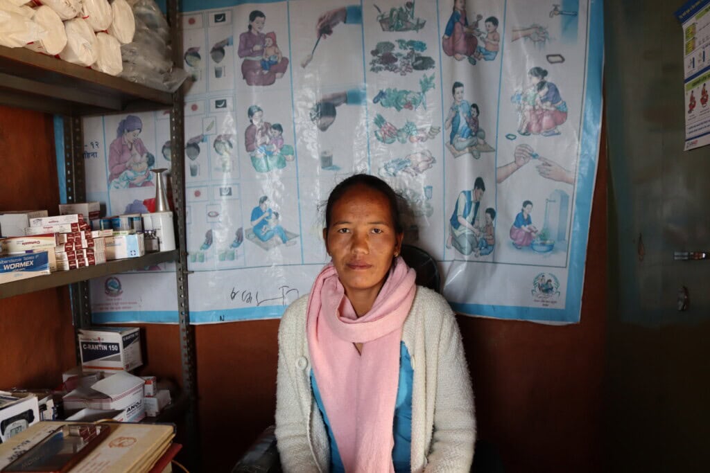 A close-up photo of Deepa Bakabal sitting inside the health post