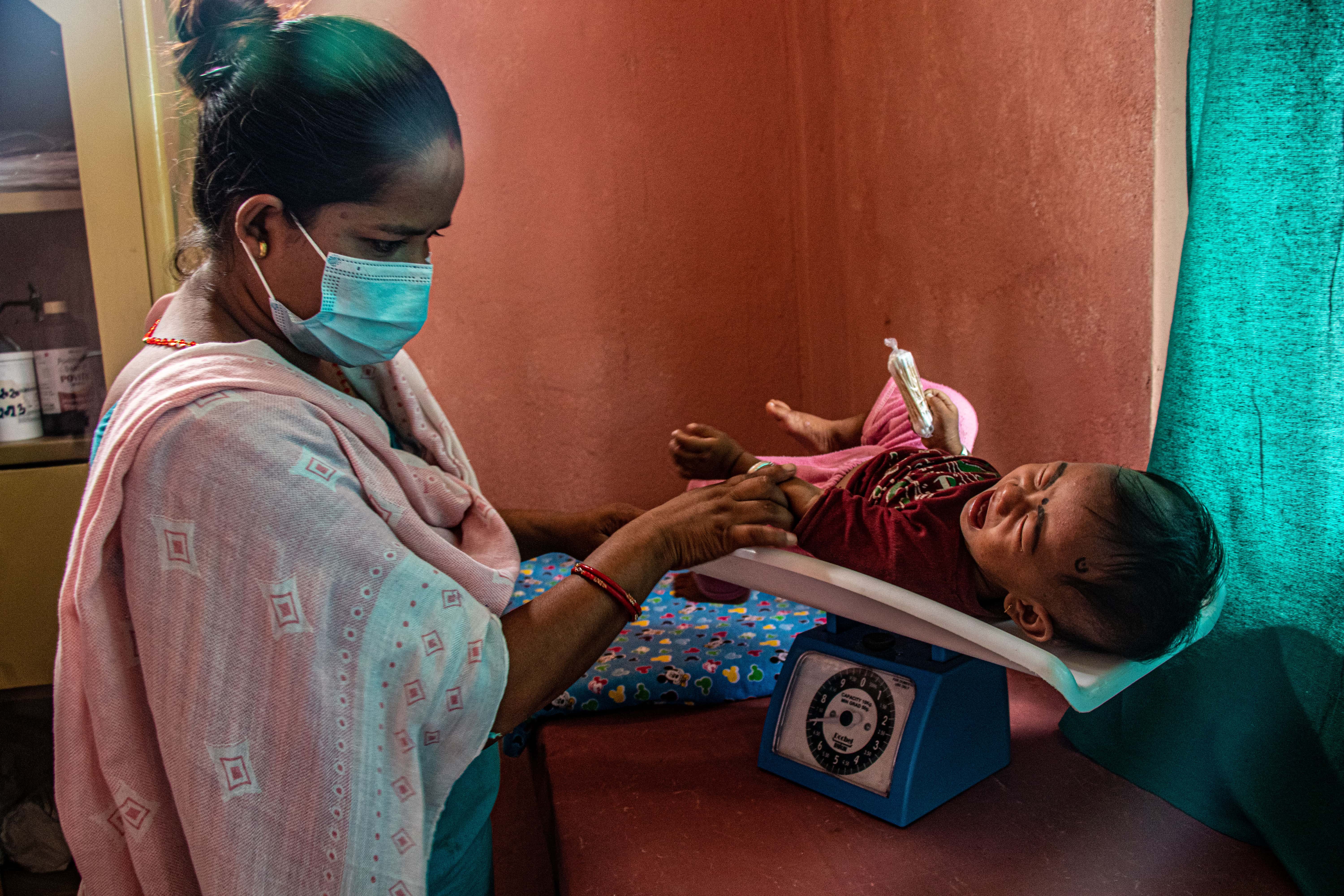 A Nepali nurse weighing a baby