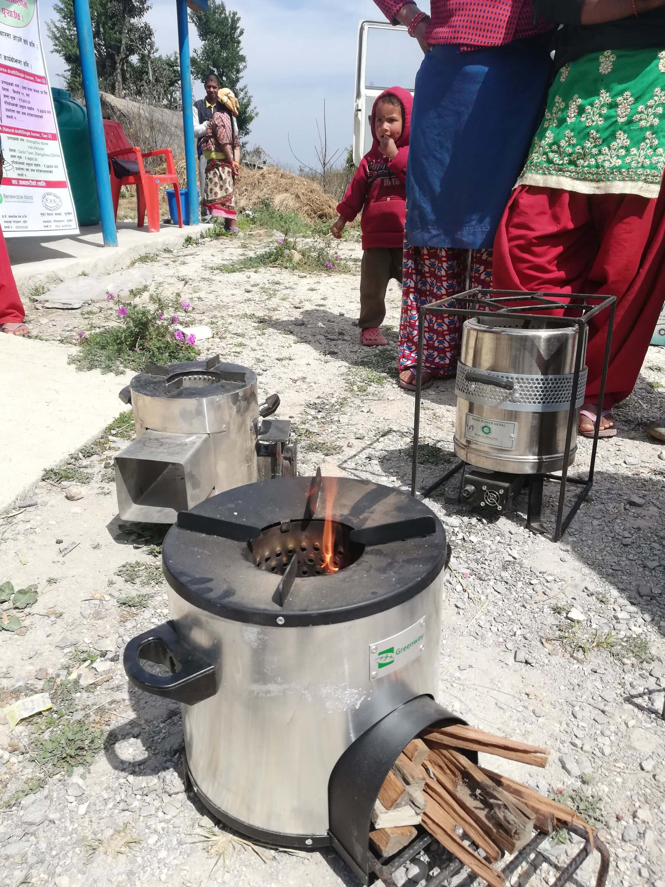 Improved cookstoves sitting on the ground with a small child in the background