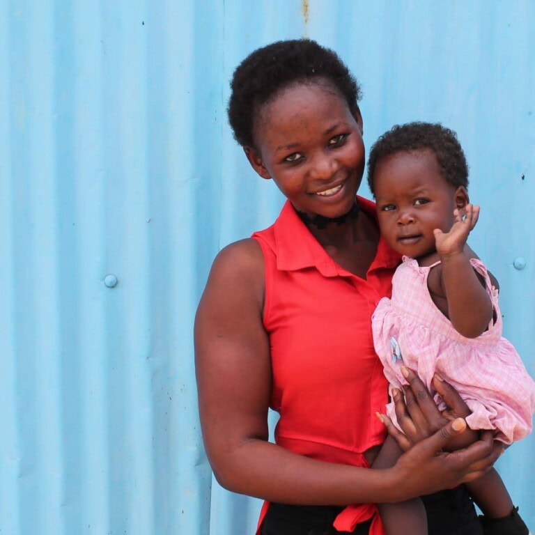 Woman in read dress with small child against blue background.
