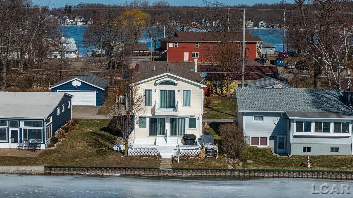 MOVE IN READY!!! Welcome to year round lakefront living on All Sports Round Lake! This 4 bedroom, 2 bath home features an open concept living area filled with natural light, highlighted by sliding doors leading to the lakefront deck which is perfect for entertaining and enjoying the water views.  The primary bedroom is a true retreat, offering a gas fireplace, sliding door to a private balcony, large windows, and spectacular lake views. The property is further complemented by a 2 bedroom, 1 bath guest apartment located above a large 2 car garage, ideal for guests, extended family, or additional income potential.  Designed to maximize lakefront living, this home offers seamless indoor-outdoor flow, abundant natural light, and breathtaking views throughout. Located on Round Lake in the Irish Hills, you can enjoy all sports recreation, year round enjoyment, and the charm of the Manitou Beach lake community while making lake life memories to last a lifetime!