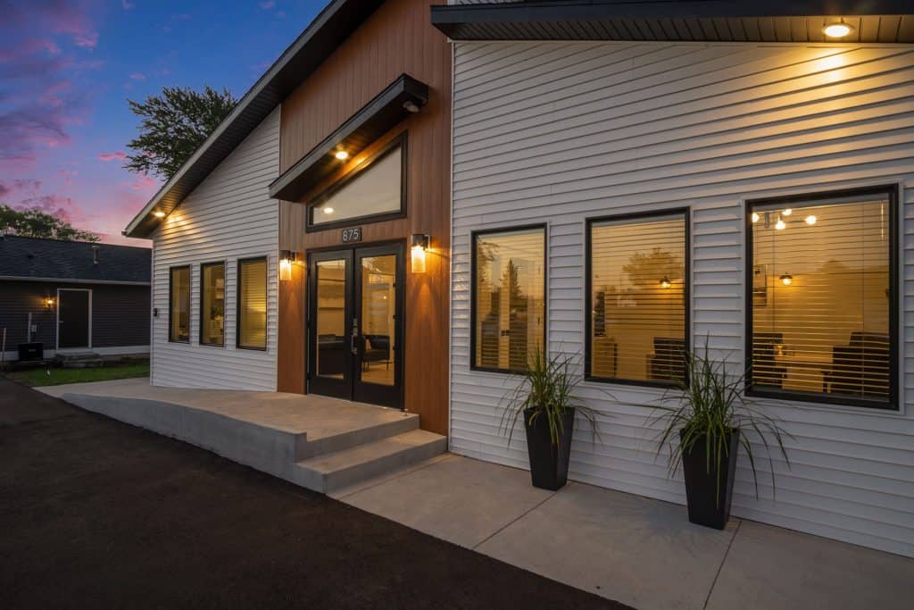 Modern new residential home exterior with stylish design and warm lighting at dusk, showcasing contemporary architecture and appealing curb appeal in West Michigan.