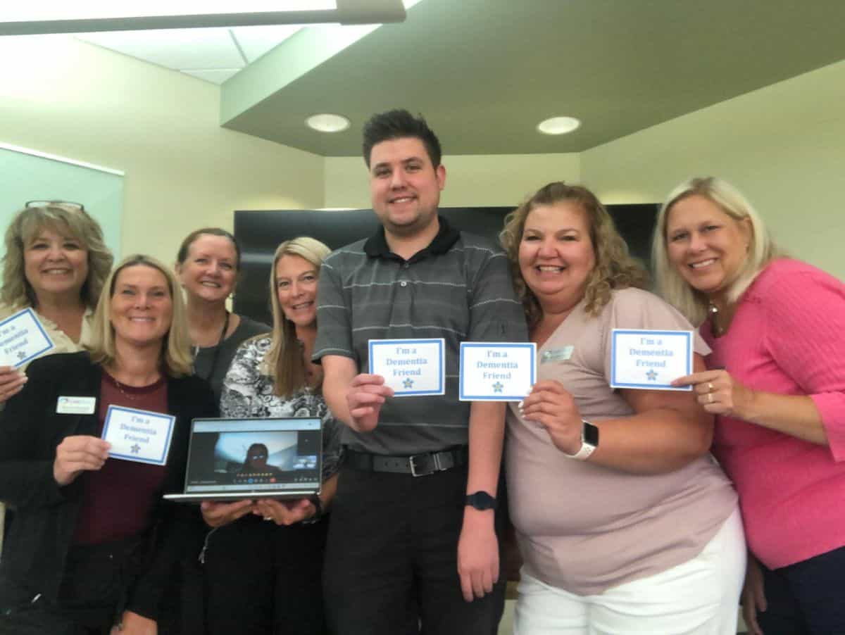 Group of smiling seniors and staff holding signs at Senior Resources event.